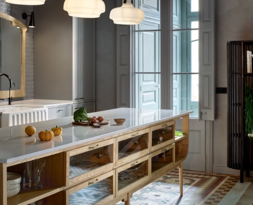 Una cocina con gabinetes de madera y una isla de madera, bellamente capturada por un talentoso fotógrafo especializado en renovaciones de diseño de interiores.