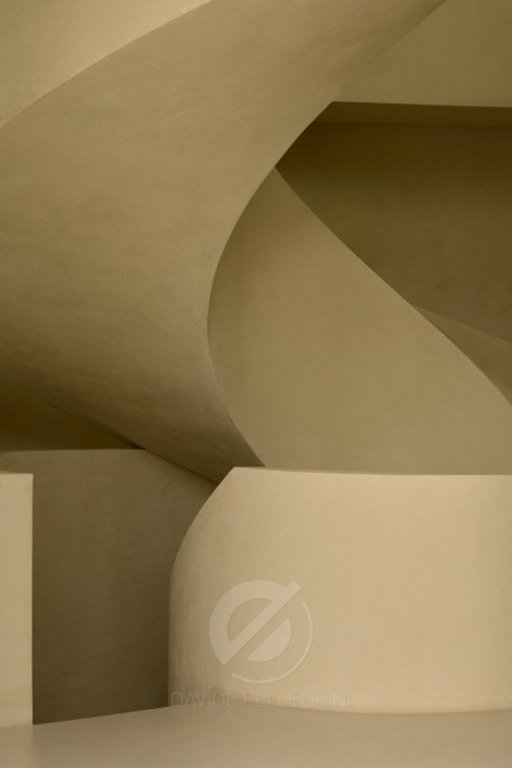 Una imagen de una escalera de caracol en un edificio beige para una sesión fotográfica editorial.