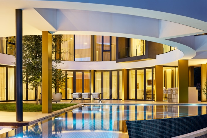 Una lujosa villa con arquitectura moderna y piscina de noche.