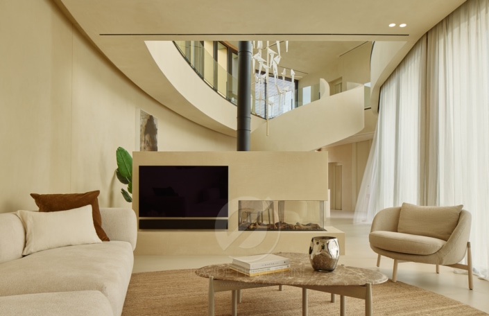 Ubicada dentro de la exquisita Villa Camiral, esta moderna sala de estar cuenta con una impresionante chimenea circular. Disfrute de un ambiente acogedor y un diseño elegante en este lugar perfecto para relajarse. (Palabras clave: Villa Camiral