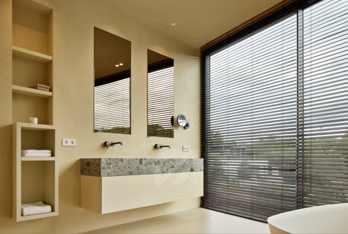 Un baño de lujo en una villa con un gran ventanal y lavabo.